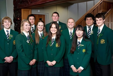 Un grupo de estudiantes en uniforme escolar verde está reunido en un pasillo de Papanui High School.