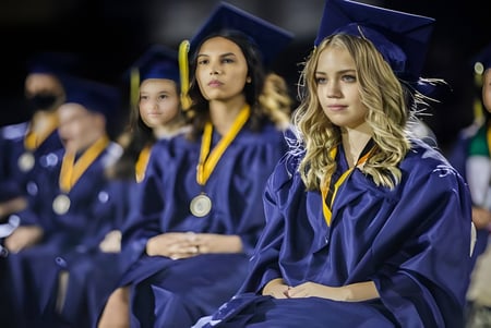 Un grupo de graduados en togas moradas está en el terreno del Paradise Valley Unified School District.