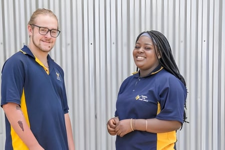 Dos personas en uniformes están frente a una pared de chapa en el terreno de la Paralowie R-12 School.