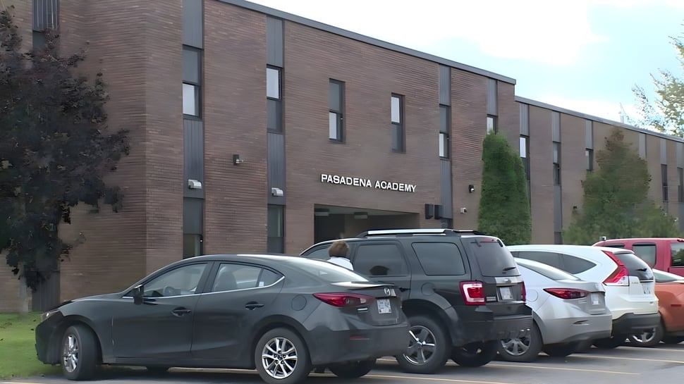 El gran edificio de ladrillo de la Pasadena Academy con coches aparcados en primer plano.