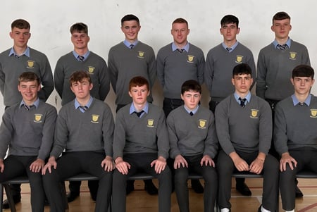Un grupo de estudiantes de la Patrician High School posan en uniforme escolar para una foto grupal formal frente a un fondo neutro.