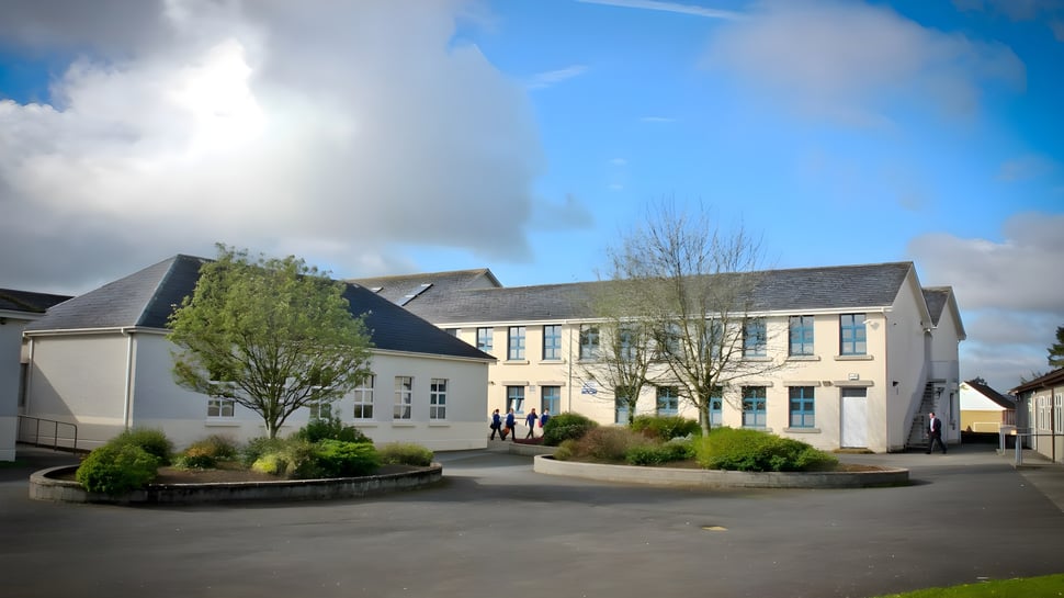 El edificio de varios pisos con patio y jardín en el campus de la Patrician Presentation Secondary School bajo un cielo nublado.