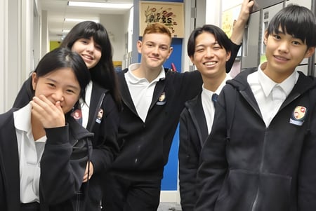 Un grupo de estudiantes en uniformes escolares está en el pasillo de la Pattison High School frente a varias decoraciones escolares.