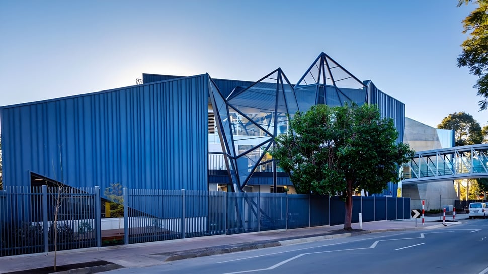 El moderno edificio de la Pembroke School con ventanas de vidrio azules y triangulares se encuentra detrás de una valla de metal.