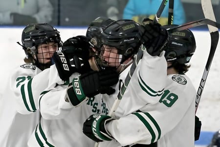 Un grupo de estudiantes con camisetas blancas y verdes juega hockey en la pista de hielo de Pender Harbour Secondary.
