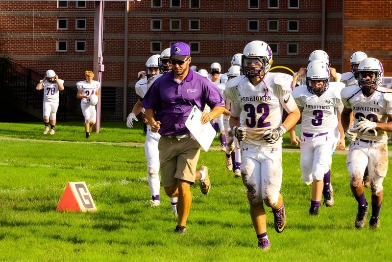 Un grupo de jugadores de fútbol en uniforme corre por un campo de hierba en el campus de la Perkiomen School.