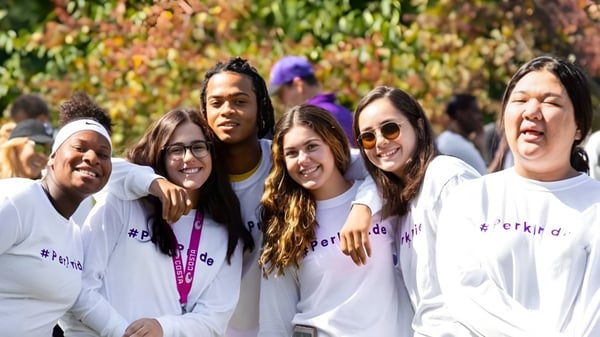 Un grupo de estudiantes sonrientes de la Perkiomen School está frente a un colorido paisaje otoñal.