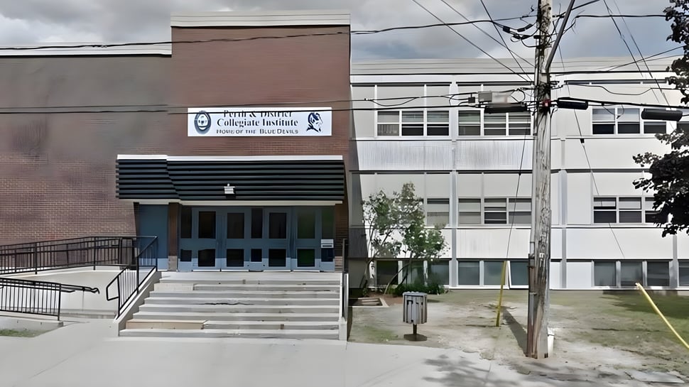 El edificio principal de varios pisos del Perth & District Collegiate Institute con escalones y líneas eléctricas en primer plano.