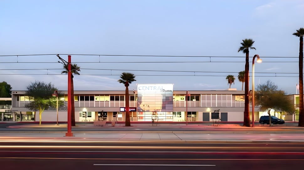 Un edificio comercial con palmeras en primer plano bajo un cielo despejado cerca del Phoenix Union High School District.