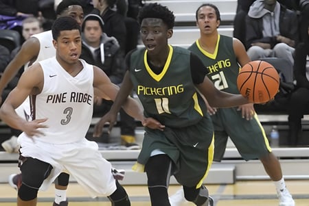 Dos jugadores de baloncesto luchan por el balón en el campo de la Pine Ridge Secondary School frente a los espectadores.