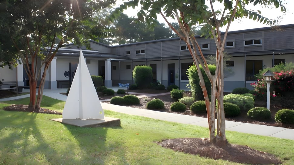 El moderno edificio de dos pisos con construcción triangular blanca se encuentra en el cuidado campus de la Pinewood Preparatory School.