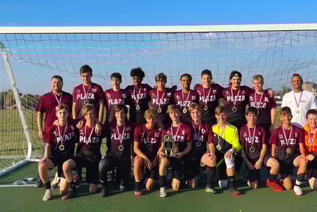 Un grupo de estudiantes de la Plaza Heights Christian Academy posan juntos en el campo de fútbol frente a la portería.