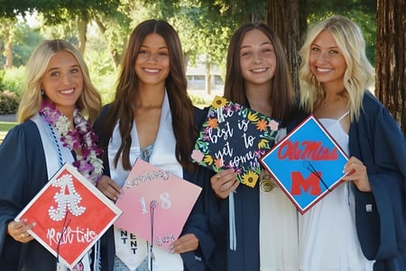 Cuatro estudiantes están sonriendo juntas en un área similar a un parque en el terreno de la Pleasant Valley High School.