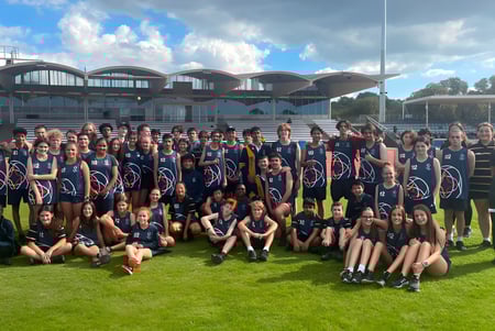 Un grupo de estudiantes del Plympton International College posan frente a un edificio moderno con forma de cúpula y un campo verde al fondo.