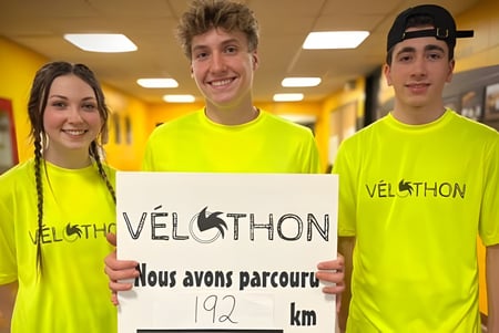 Tres estudiantes de la Polyvalente Louis-J.-Robichaud llevan camisetas amarillas de VELOTHON y sostienen un cartel con la inscripción 192 km.