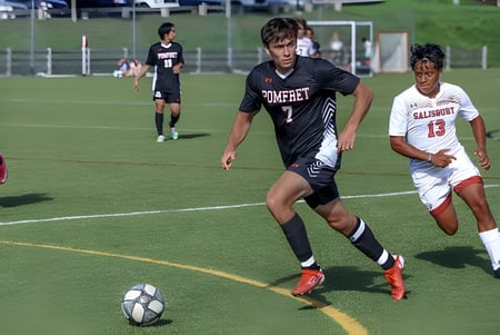 Dos estudiantes de la Pomfret School juegan en el campo de fútbol por el balón con la portería al fondo.