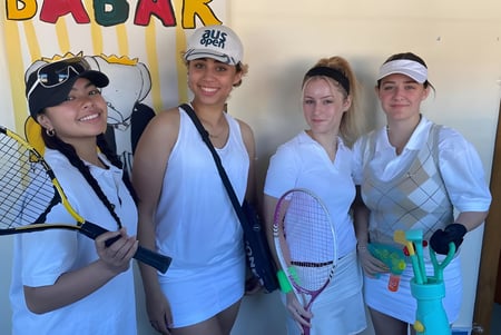 Cuatro alumnas de la Port Hacking High School posan juntas frente al colorido cartel de Badark.