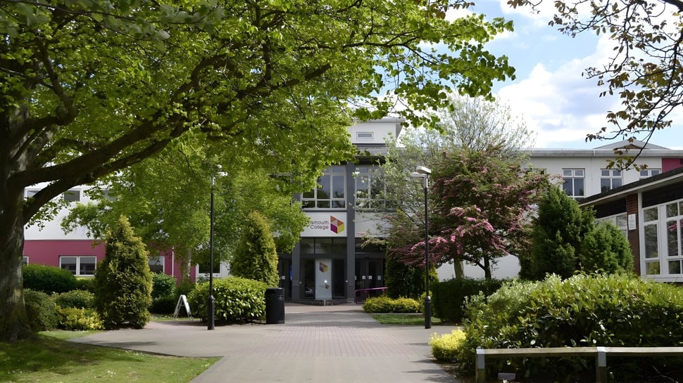 Un jardín bien cuidado con árboles y arbustos en flor a lo largo de un camino en el campus del Portsmouth College.