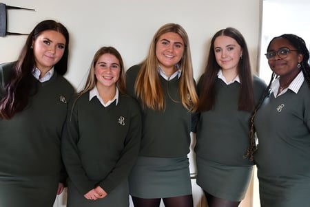 Un grupo de cinco alumnas en uniformes escolares verdes está de pie juntas en el campus de la Presentation Secondary School en Cork.