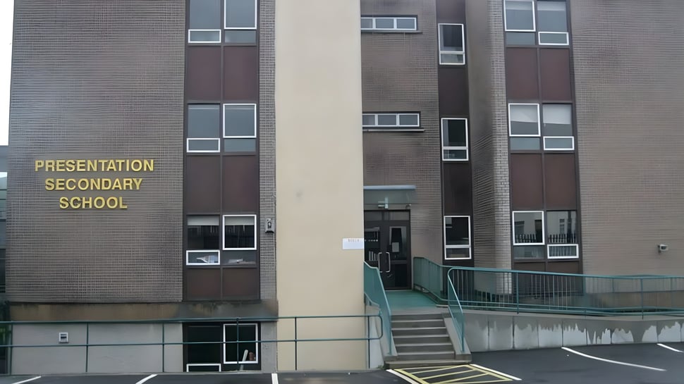 Se puede ver el edificio de ladrillo de varios pisos de la Presentation Secondary School en Cork con un estacionamiento alrededor.