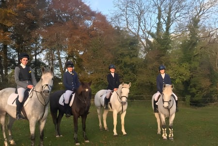 Estudiantes de la Presentation Secondary School en Tipperary montan a caballo al aire libre en un entorno paisajístico.