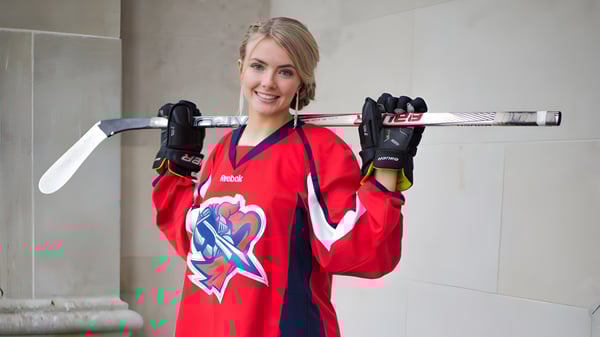 Una alumna del Prince of Wales Collegiate está con un stick de hockey frente a una pared de concreto.