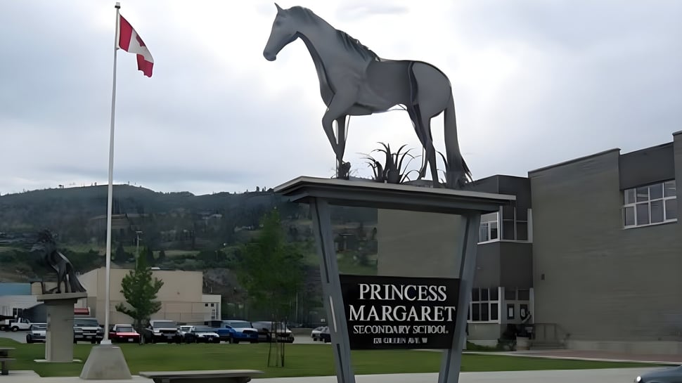 Una gran estatua de caballo se encuentra en el terreno de la Princess Margaret Secondary School frente a un edificio y una bandera canadiense.