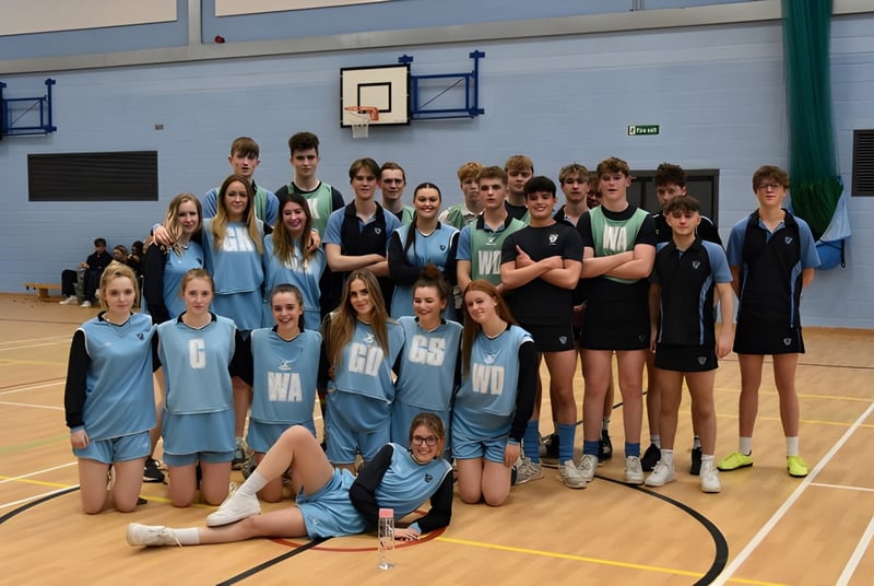 Un grupo de estudiantes del Prior Park College posan en el gimnasio con canastas de baloncesto al fondo.
