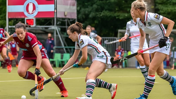 Alumnas de la Prior’s Field School juegan un partido de hockey sobre campo en el terreno deportivo con gradas de espectadores al fondo.