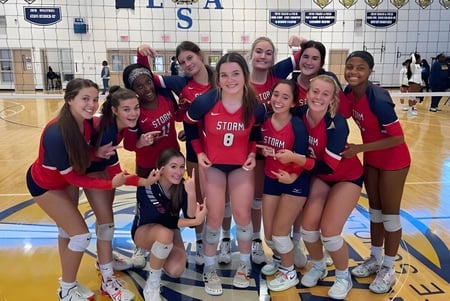 Un grupo de alumnas de voleibol de la Providence Christian Academy posan juntas en una cancha de baloncesto.