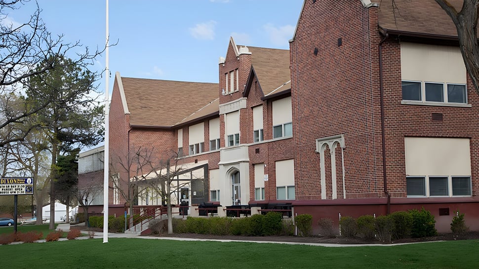 El edificio de ladrillo con arquitectura distintiva en el campus del Provo City School District está rodeado de un área verde y árboles.
