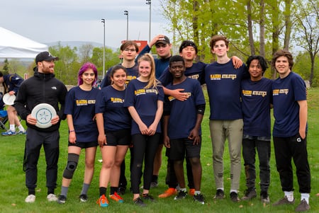 Un grupo de estudiantes de la Québec High School está posando juntos como un equipo deportivo en un campo.