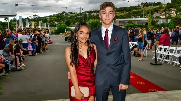 Estudiantes de la Queechy High School posan con ropa formal en la alfombra roja frente a una multitud.