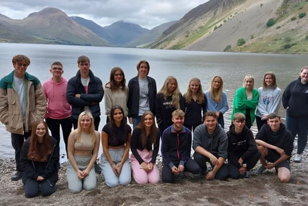 Estudiantes de Queen Elizabeth’s 6th Form están juntos frente a un lago de montaña con cumbres nevadas.