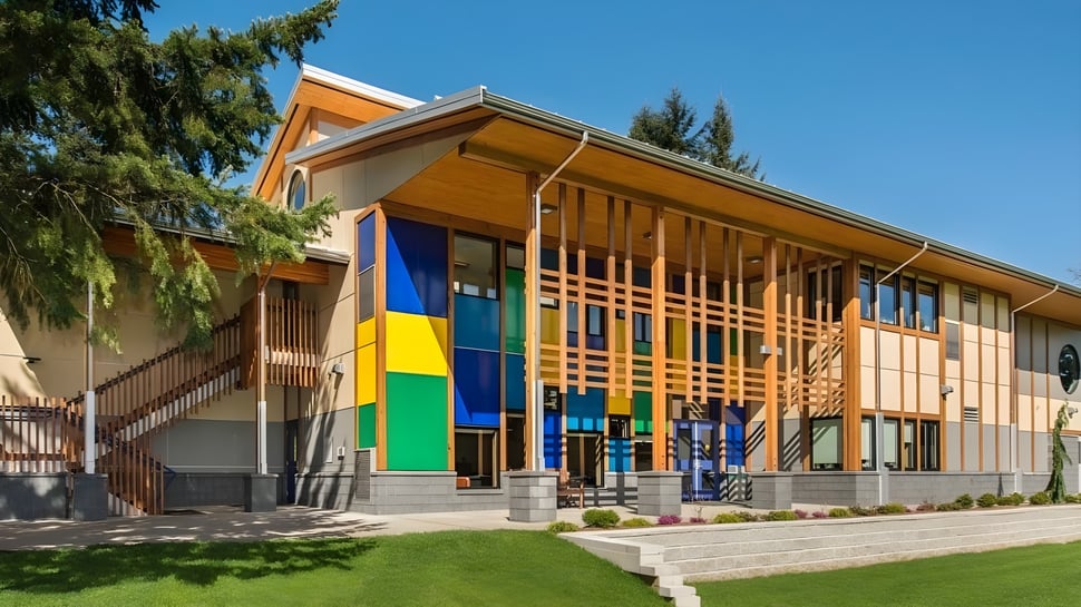 El moderno y colorido edificio de Queen Margaret’s School está en un área verde con árboles bajo un cielo azul.