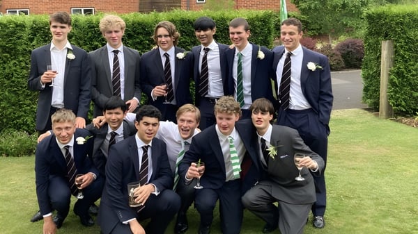 Un grupo de estudiantes del Radley College posan frente a un edificio de ladrillo con un entorno verde.