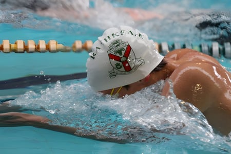 Un nadador con gorra de baño salta a una piscina en el campus de Rathkeale College.
