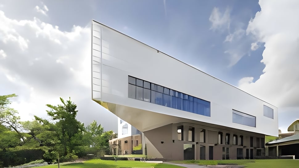 El moderno edificio blanco de la Ravenswood School for Girls está rodeado de árboles verdes bajo un cielo azul.