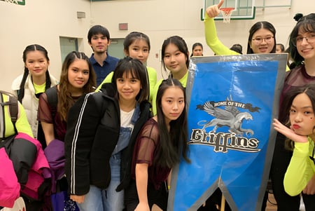 Un grupo de estudiantes de la R.C. Palmer Secondary School posa con un gran banner azul con el logo del equipo deportivo.