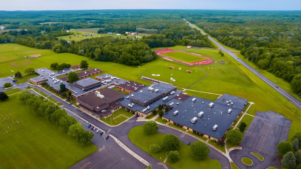 Paisaje con campo de deportes y edificios en el terreno de la Red Creek High School en el área rural.