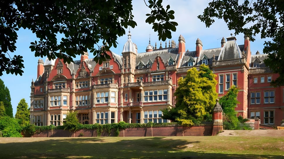 El edificio principal gótico de Reddam House Berkshire está rodeado de césped bien cuidado y un jardín verde.