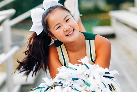 Una estudiante de la Redmond High School con una cinta blanca en el cabello sonríe frente a un fondo verde.