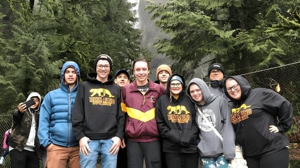 Un grupo de estudiantes está en el bosque en el terreno de la Redmond High School.