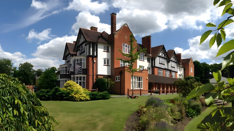 El edificio Tudor de la Reed’s School está rodeado de un jardín bien cuidado con césped y follaje verde.