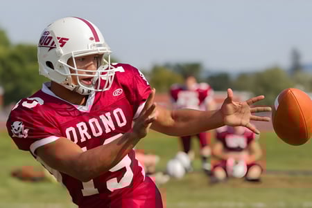 Un futbolista con camiseta roja atrapa el balón en el campo de la Regional School Unit N*26.
