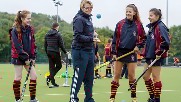 Un grupo de estudiantes del Rendcomb College está en uniforme deportivo en un campo frente a un área boscosa.