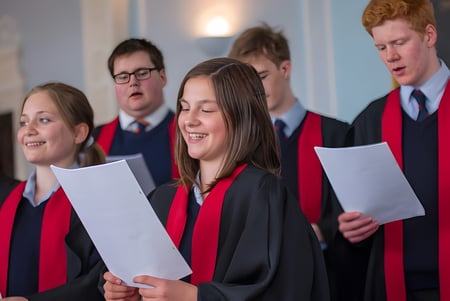 Un grupo de estudiantes en ropa de graduación sostiene diplomas y está junto en el Rendcomb College.
