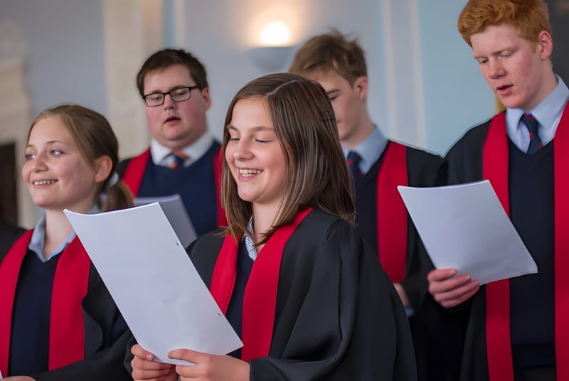 Un grupo de estudiantes en ropa de graduación sostiene diplomas y está junto en el Rendcomb College.