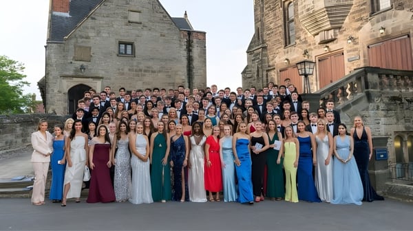 Un gran grupo de estudiantes en traje formal está frente al histórico edificio de piedra en el campus de la Repton School.