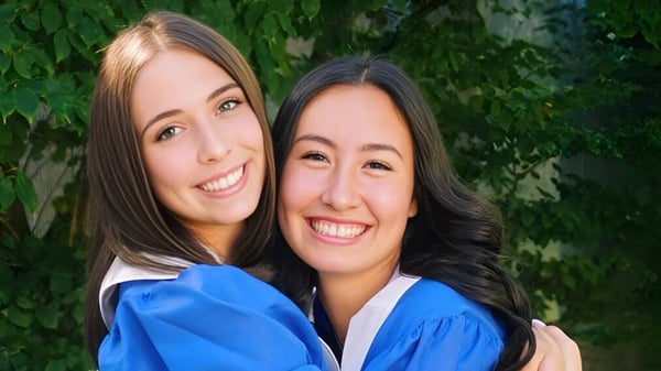 Dos estudiantes de la Reynolds Secondary School están juntas frente a un fondo verde y sonríen.